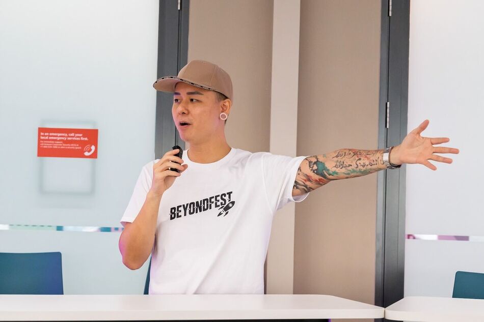 Speaker in a BeyondFest tee throwing an arm wide mid Knowledge Share
