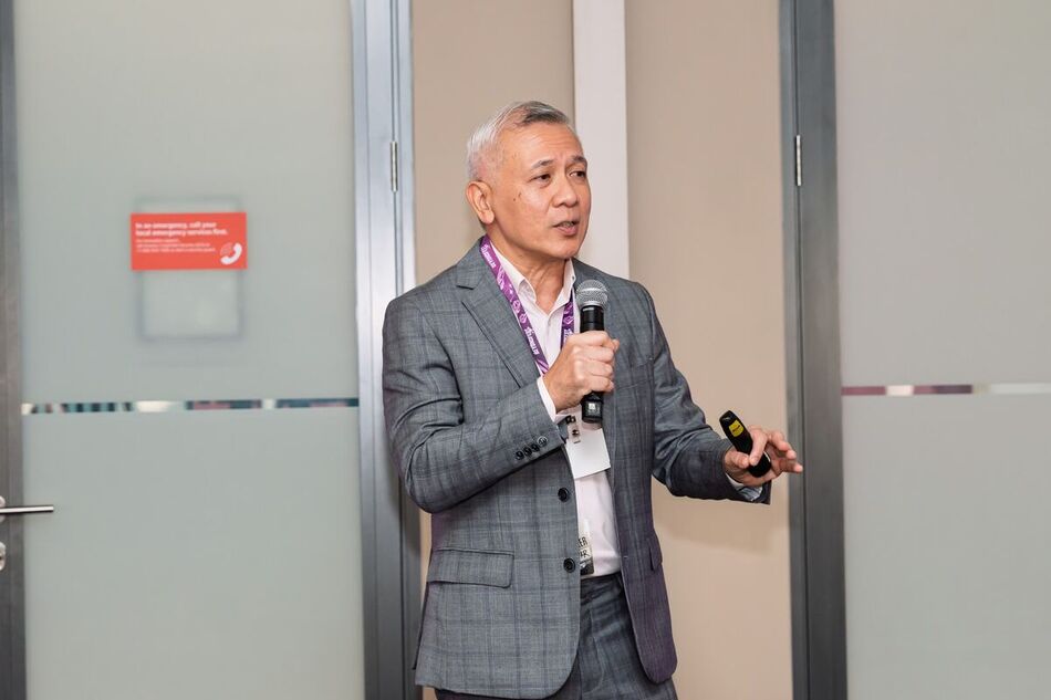 Speaker in a grey suit working the room on a handheld mic