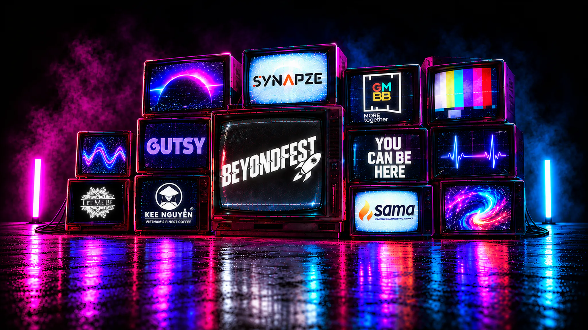 Wall of CRT televisions glowing purple and blue on a wet floor: the centre screen reads BeyondFest, the others carry the Synapze, GMBB, Gutsy, SAMA, Kee Nguyen Vietnam Coffee and Let Me Be partner logos and one reads YOU CAN BE HERE