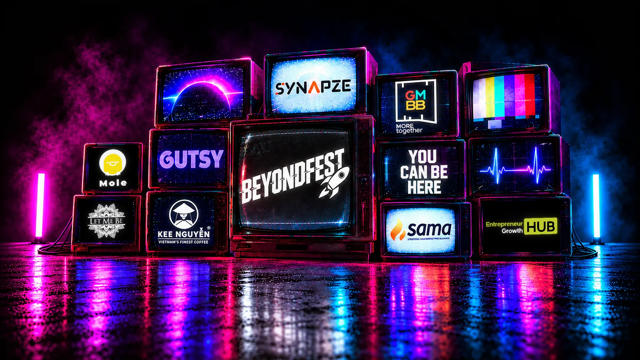 Wall of CRT televisions glowing purple and blue on a wet floor: the centre screen reads BeyondFest, the others carry the Synapze, GMBB, Gutsy, SAMA, Kee Nguyen Vietnam Coffee, Let Me Be, Mole and Entrepreneur Growth Hub partner logos and one reads YOU CAN BE HERE