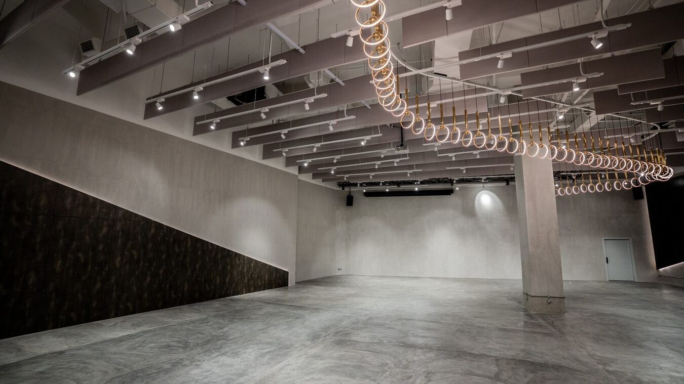 The Grey Box main hall, a long concrete room under a spiral of filament bulbs